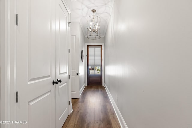 doorway featuring dark wood-style floors, baseboards, and a chandelier