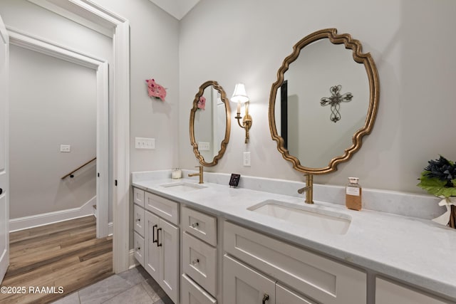 bathroom featuring double vanity, wood finished floors, and a sink