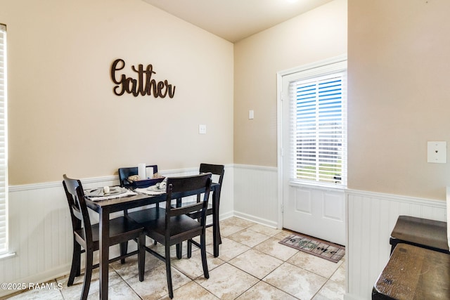 dining area with wainscoting and light tile patterned floors