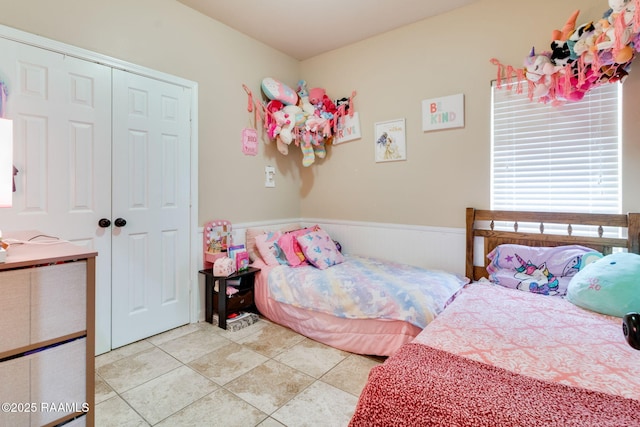 bedroom featuring a closet, wainscoting, and tile patterned floors