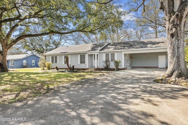 ranch-style home featuring an attached carport, concrete driveway, and a front yard