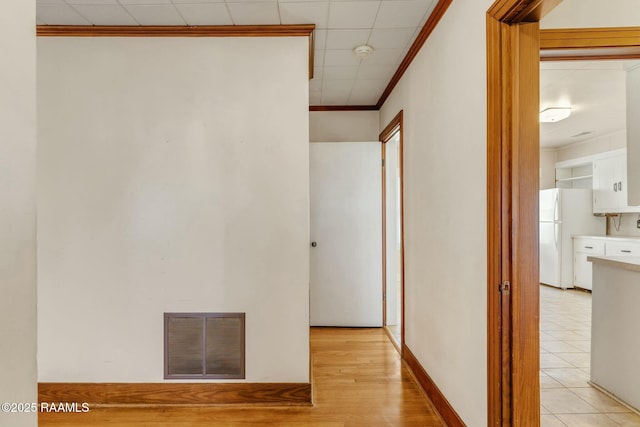 hall with light tile patterned floors, visible vents, and crown molding