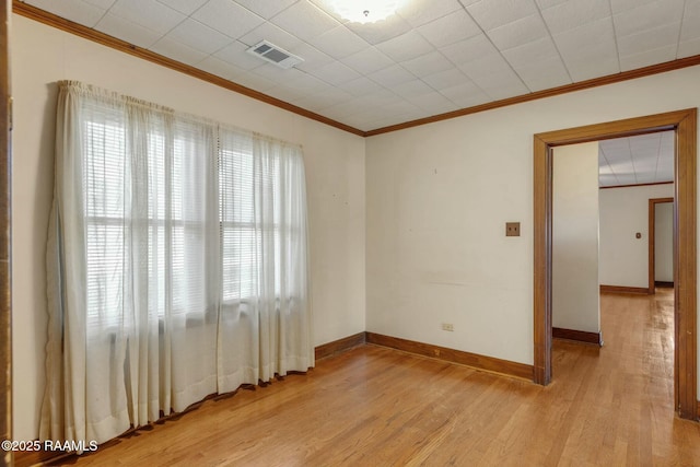 unfurnished room featuring visible vents, baseboards, light wood-style floors, and crown molding