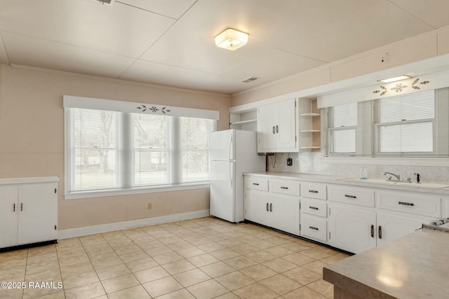 kitchen featuring open shelves, a sink, white cabinetry, freestanding refrigerator, and crown molding