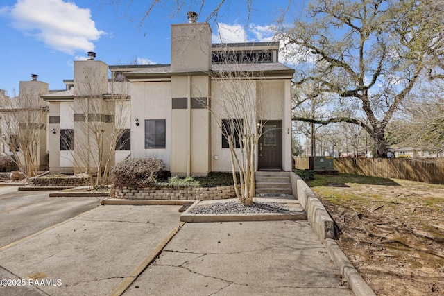 exterior space featuring fence, a chimney, and stucco siding