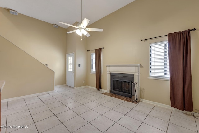 unfurnished living room with a fireplace with flush hearth, ceiling fan, high vaulted ceiling, and light tile patterned floors