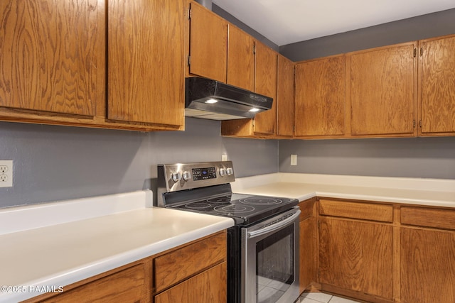 kitchen featuring brown cabinets, electric stove, light countertops, and under cabinet range hood