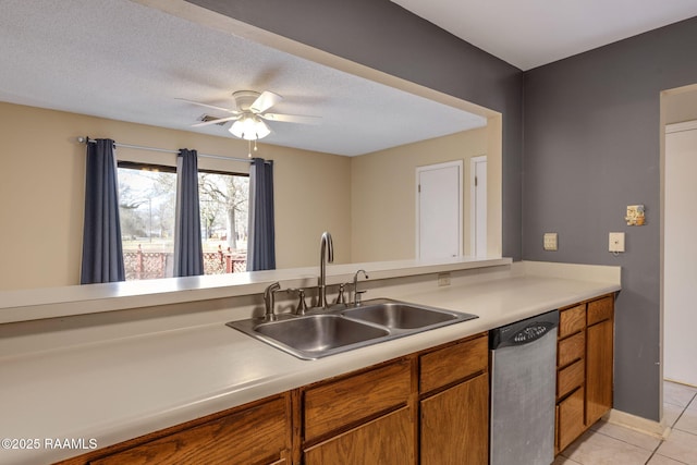 kitchen with light tile patterned floors, a sink, light countertops, dishwasher, and brown cabinetry