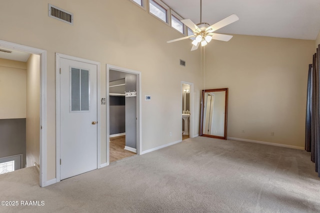 unfurnished bedroom featuring carpet floors, a walk in closet, visible vents, and high vaulted ceiling