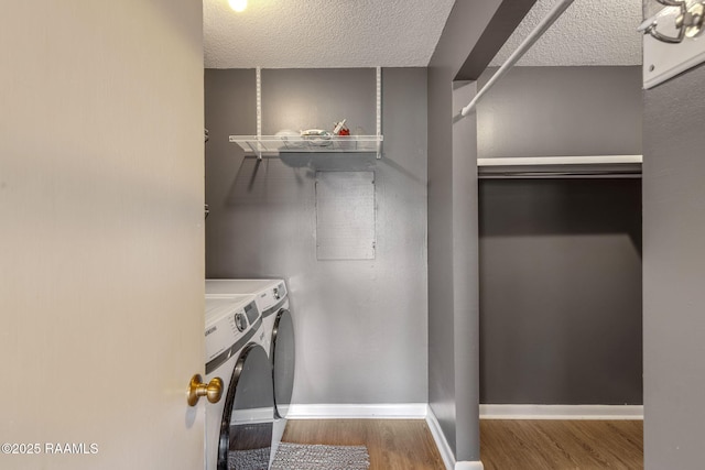 laundry area with laundry area, baseboards, washing machine and clothes dryer, and wood finished floors