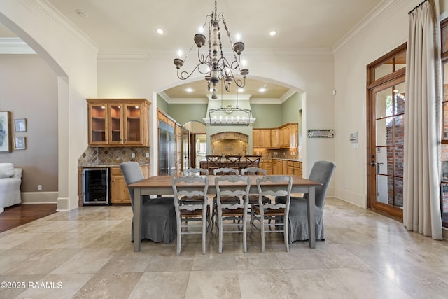 dining room with an inviting chandelier, beverage cooler, crown molding, and a wealth of natural light