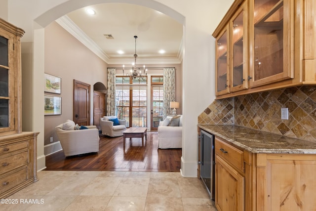 kitchen featuring tasteful backsplash, visible vents, dark stone counters, wine cooler, and crown molding