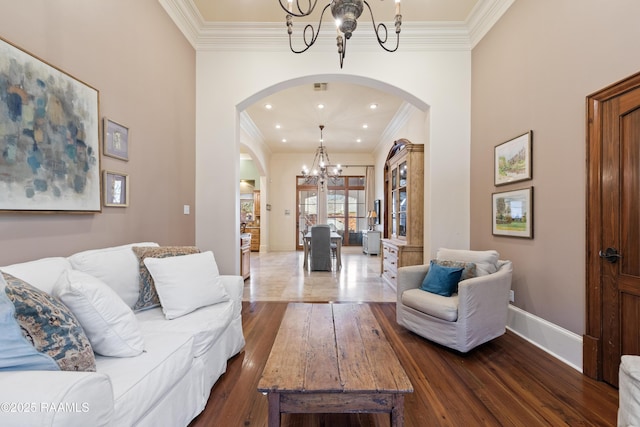 living area featuring arched walkways, ornamental molding, dark wood-style flooring, and an inviting chandelier