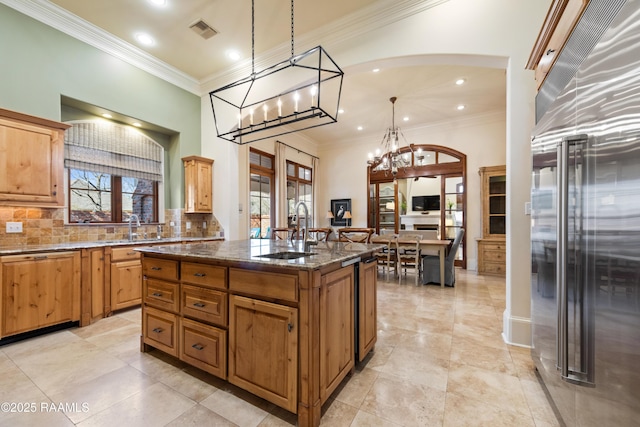 kitchen featuring tasteful backsplash, visible vents, dark stone countertops, built in refrigerator, and a sink