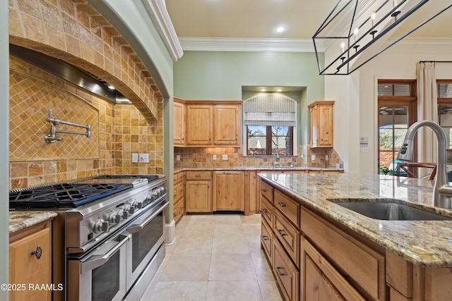 kitchen with a healthy amount of sunlight, ornamental molding, range with two ovens, and a sink