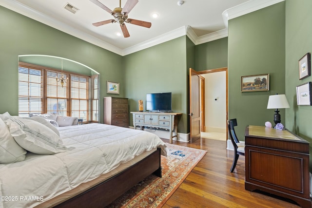 bedroom featuring visible vents, ornamental molding, ceiling fan, wood finished floors, and baseboards