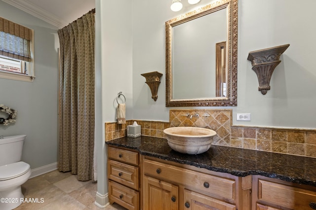 bathroom featuring crown molding, backsplash, toilet, vanity, and baseboards