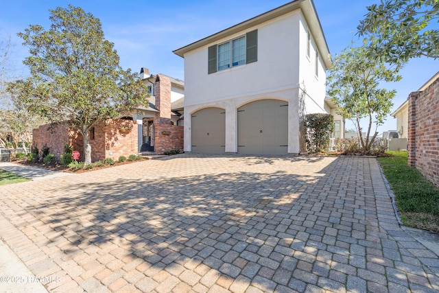 view of front of house with a garage, decorative driveway, and stucco siding