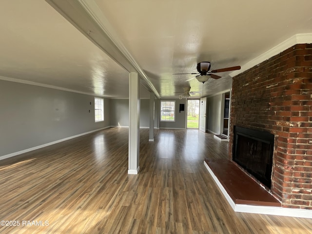 unfurnished living room with ornamental molding, dark wood-type flooring, a brick fireplace, and ceiling fan