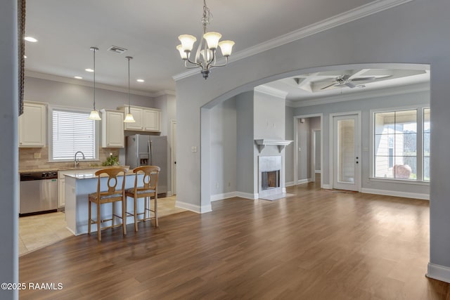 kitchen with appliances with stainless steel finishes, open floor plan, a kitchen island, and hanging light fixtures