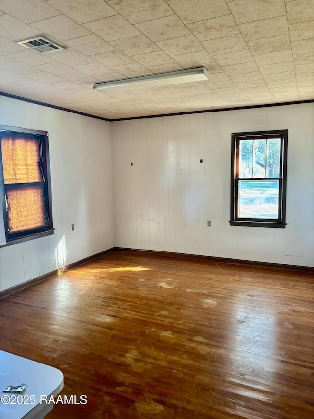 unfurnished room featuring wood finished floors, visible vents, and baseboards