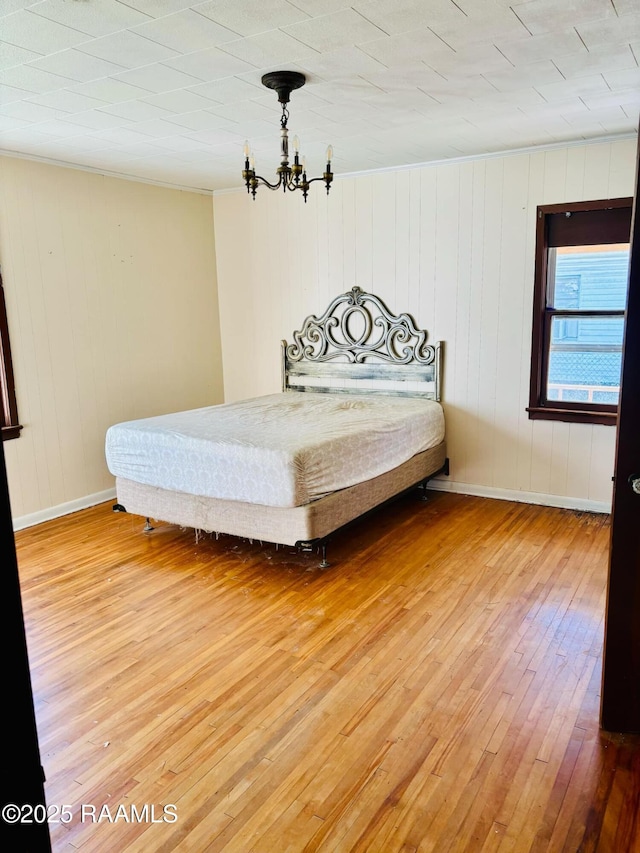 unfurnished bedroom with baseboards, an inviting chandelier, and wood finished floors