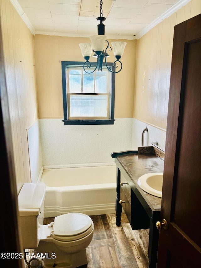 bathroom featuring ornamental molding, wood finished floors, vanity, and a bath