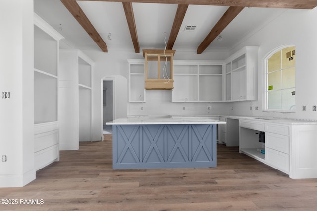 kitchen featuring light wood-type flooring, white cabinetry, a kitchen island, and tasteful backsplash