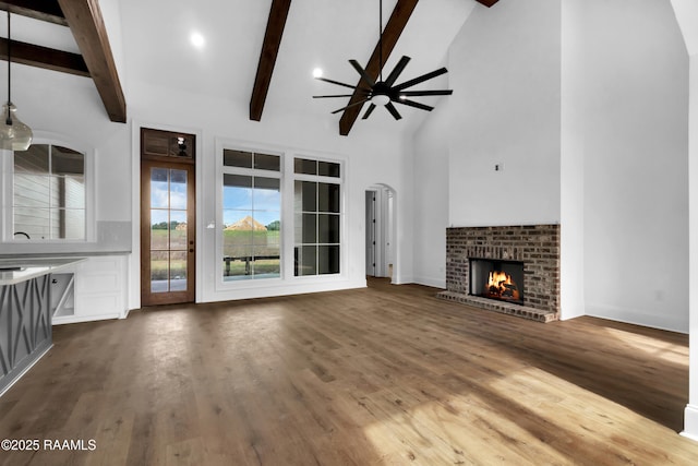 134 Cypress Bend Rd, Scott, LA 70583 - unfurnished living room featuring ceiling fan, a fireplace, beamed ceiling, dark wood-style floors, and high vaulted ceiling