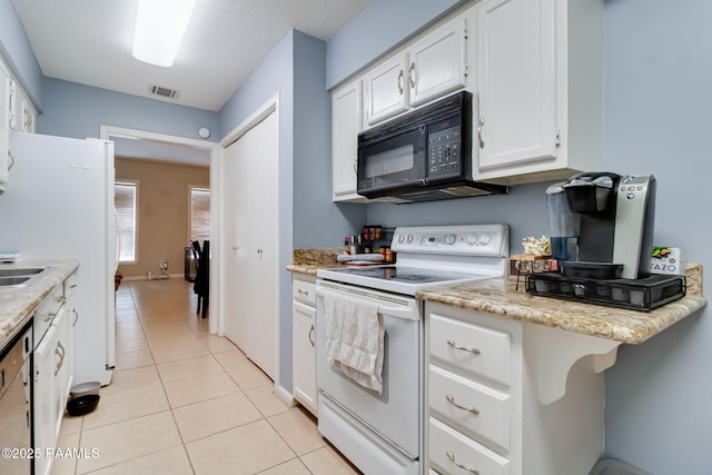 kitchen with white appliances, light tile patterned floors, visible vents, white cabinets, and a textured ceiling