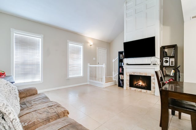 living area with visible vents, baseboards, vaulted ceiling, a fireplace, and light tile patterned flooring