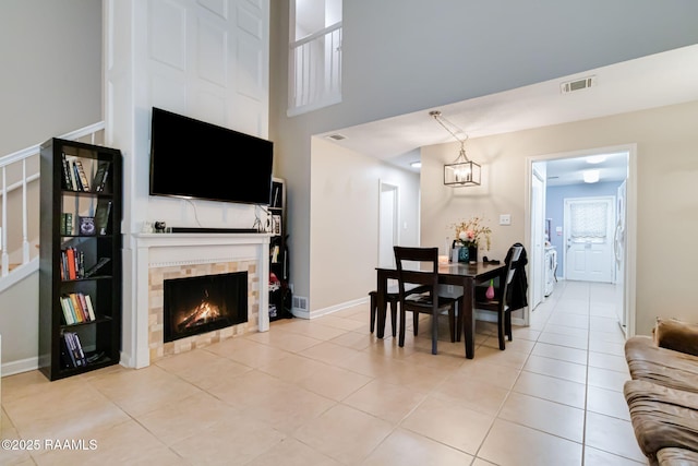 dining space with baseboards, visible vents, a tiled fireplace, and light tile patterned floors