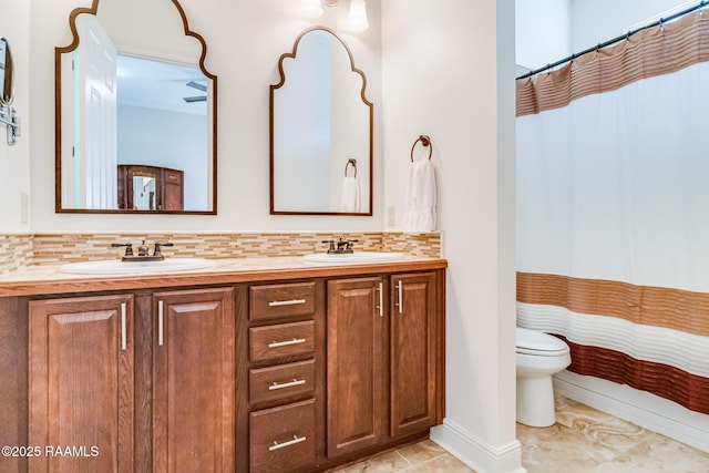 bathroom featuring double vanity, backsplash, a sink, and toilet