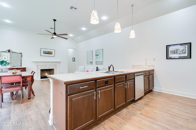 kitchen with open floor plan, light countertops, stainless steel dishwasher, pendant lighting, and a sink