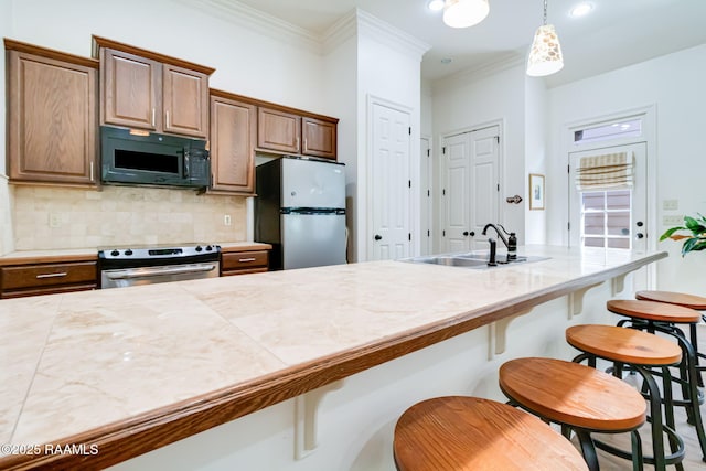 kitchen with appliances with stainless steel finishes, brown cabinets, a kitchen bar, pendant lighting, and a sink