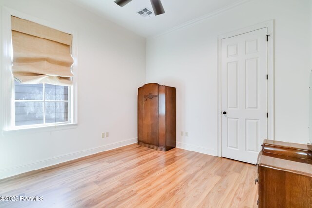 unfurnished bedroom with ceiling fan, light wood-style flooring, visible vents, baseboards, and ornamental molding