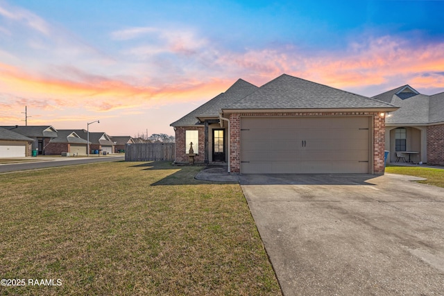 view of front of house featuring brick siding, a shingled roof, concrete driveway, an attached garage, and a front yard