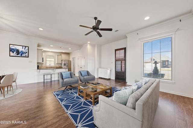 living room with baseboards, wood finished floors, a wealth of natural light, and crown molding