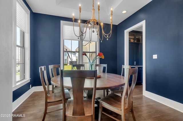 dining space featuring an inviting chandelier, wood finished floors, and baseboards