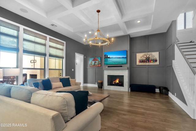 living area featuring a lit fireplace, visible vents, a chandelier, and coffered ceiling