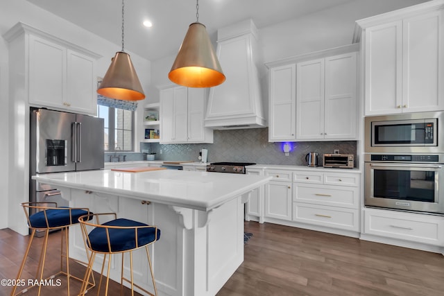 kitchen featuring dark wood-style floors, light countertops, premium range hood, decorative backsplash, and appliances with stainless steel finishes