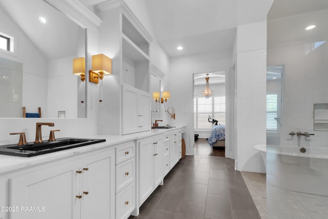 ensuite bathroom featuring recessed lighting, double vanity, a sink, connected bathroom, and a freestanding tub