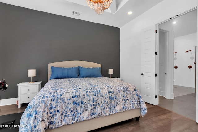 bedroom featuring an inviting chandelier, wood finished floors, visible vents, and recessed lighting