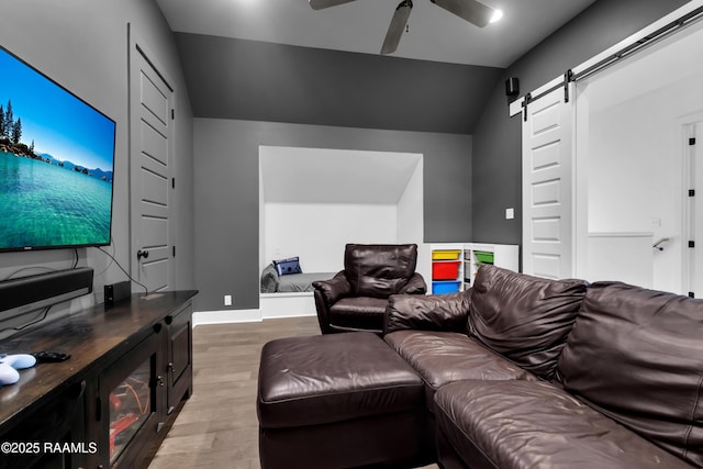 cinema with a barn door, light wood-style floors, lofted ceiling, and ceiling fan