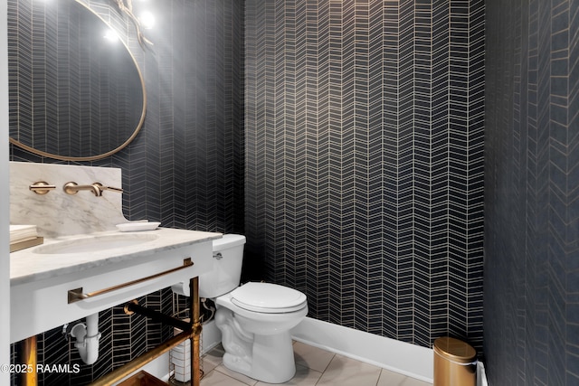 half bath featuring tile patterned flooring, tile walls, toilet, and a sink