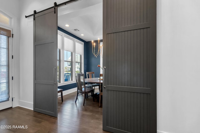 dining room featuring a barn door, a notable chandelier, visible vents, baseboards, and dark wood-style flooring