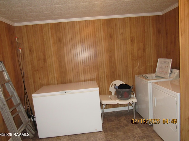 clothes washing area featuring ornamental molding, wooden walls, and washing machine and clothes dryer