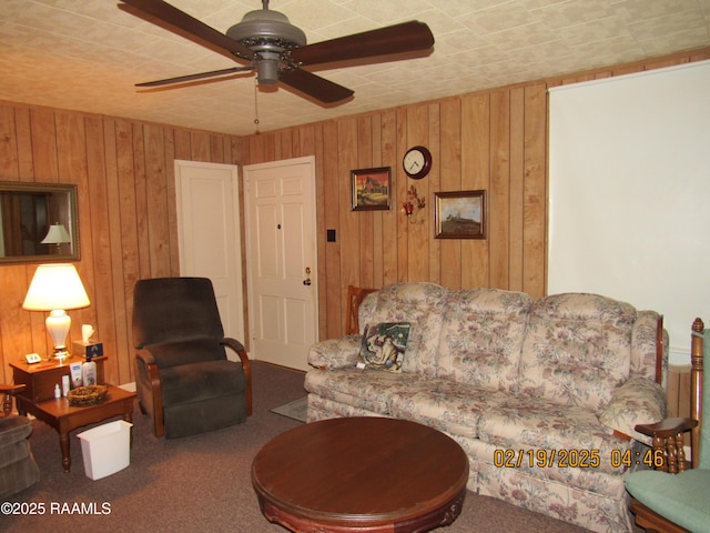 carpeted living room featuring ceiling fan and wood walls