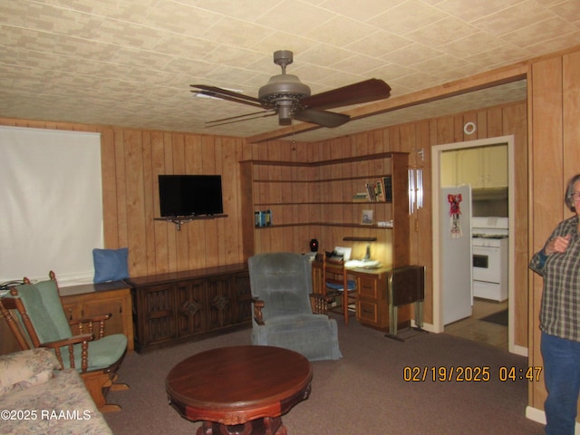 living area with carpet flooring, wooden walls, and ceiling fan