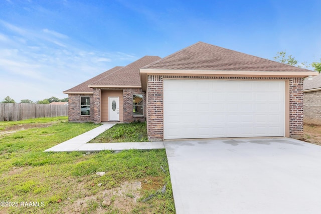 view of front of property with fence, a shingled roof, concrete driveway, brick siding, and a front yard